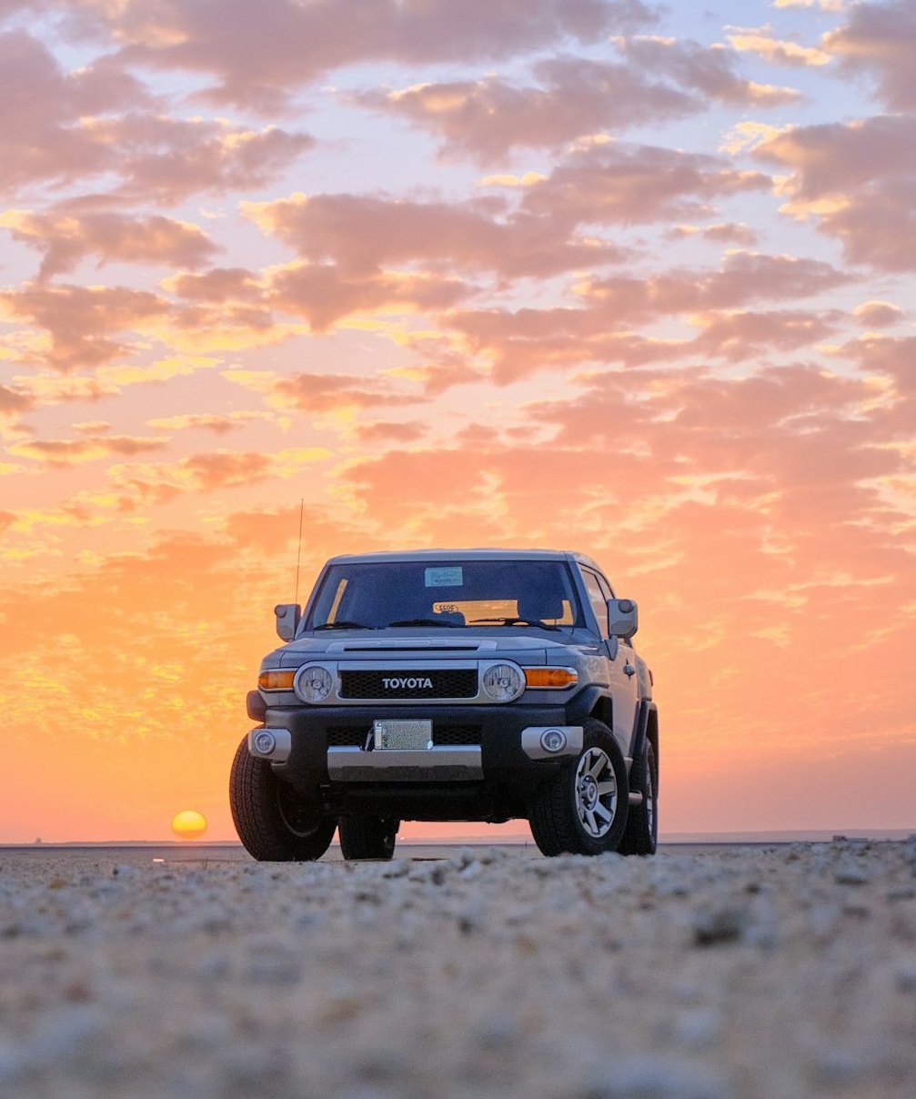 A 4x4 on a desert flat at sunset