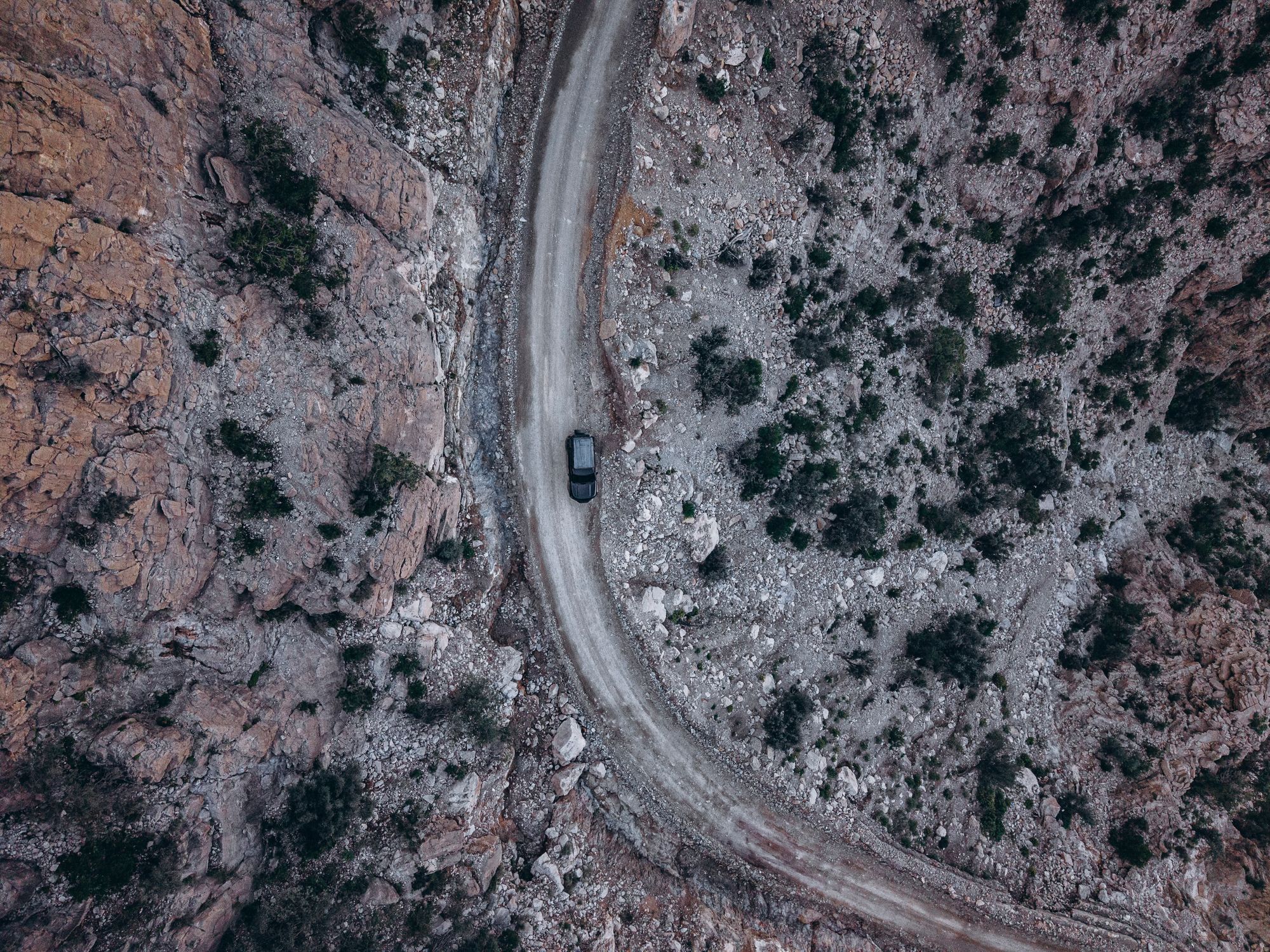 A car on a winding mountain road, seen from above